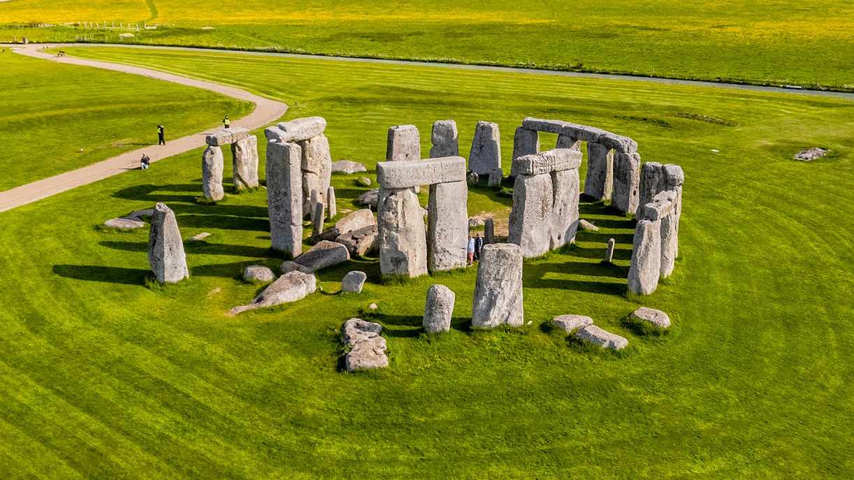 Tourists walking around Stonehenge on a day trip from London.