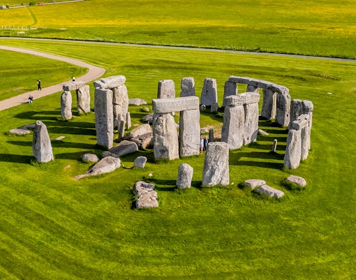 Tourists walking around Stonehenge on a day trip from London.