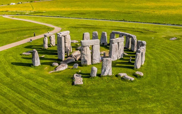 Tourists walking around Stonehenge on a day trip from London.