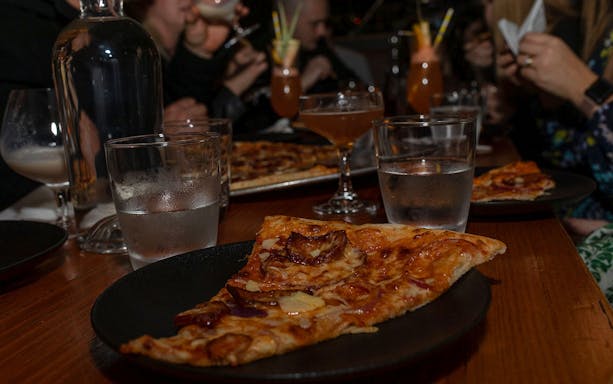 Pizza and cocktails on a table during Melbourne's hidden bars tour.