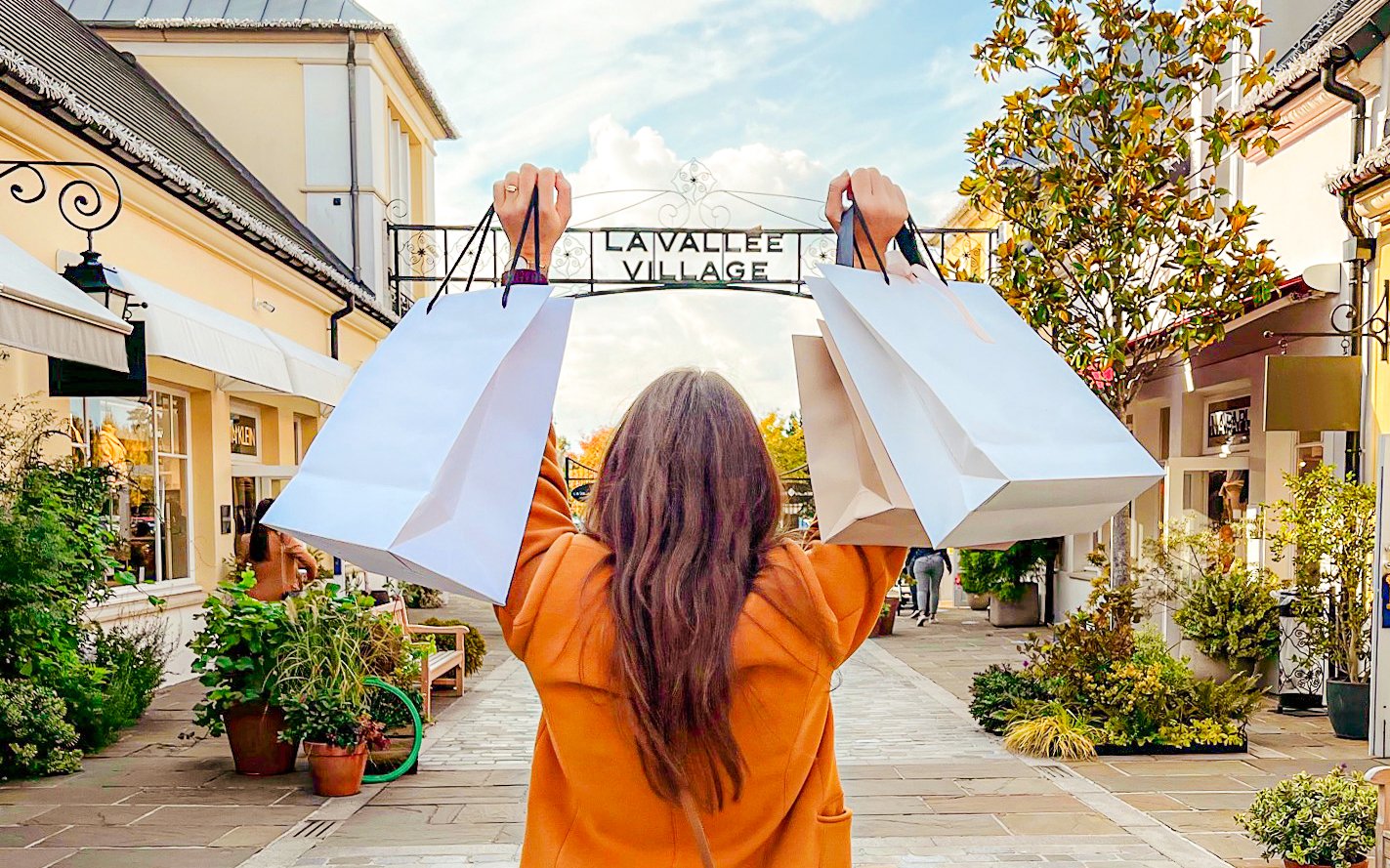 Shopper holding bags at La Vallee Village, Paris, France.