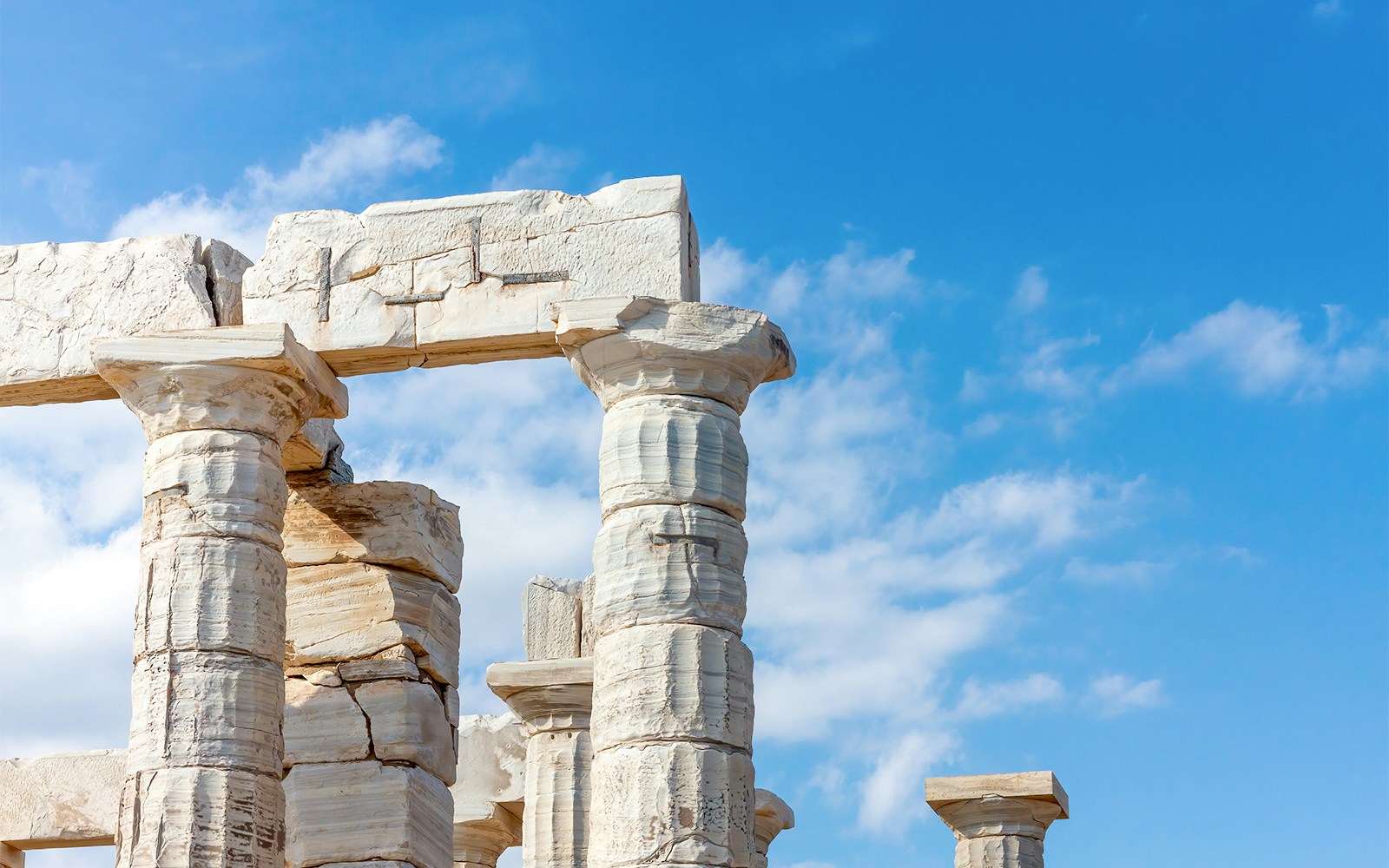 Ancient Doric columns of the Temple of Poseidon in Sounion, Greece against blue sky.