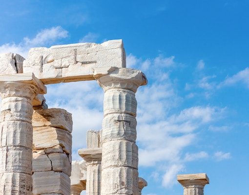 Ancient Doric columns of the Temple of Poseidon in Sounion, Greece against blue sky.