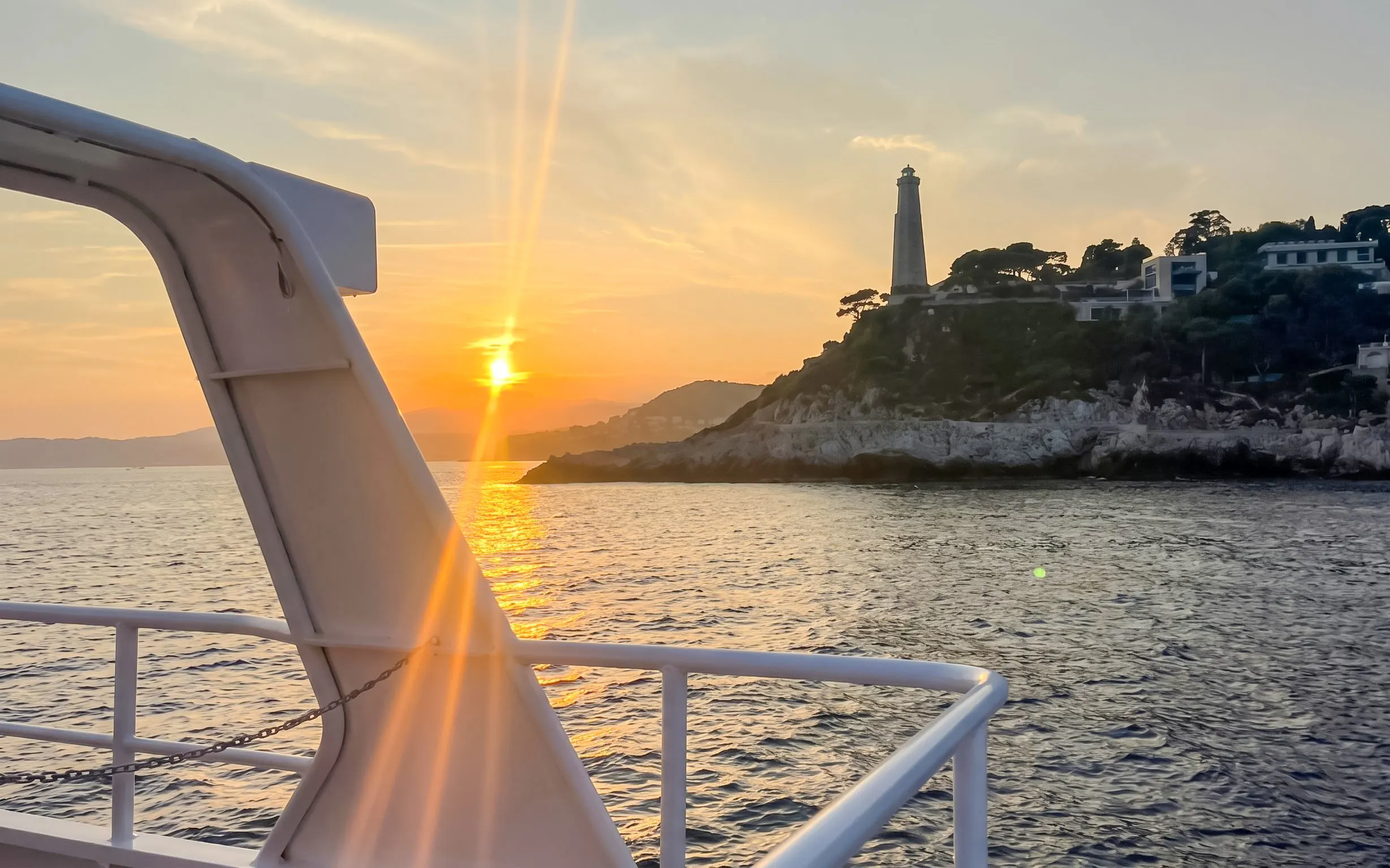 Sunset view from boat near Villefranche lighthouse on a scenic tour.