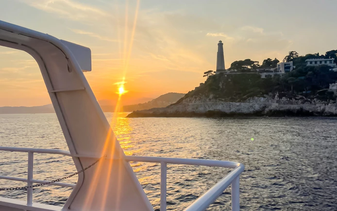 Sunset view from boat near Villefranche lighthouse on a scenic tour.