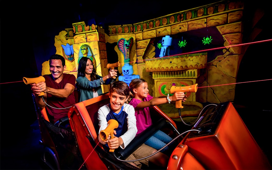 Visitors enjoying the Lost Kingdom ride at LEGOLAND Florida, aiming laser guns at targets.
