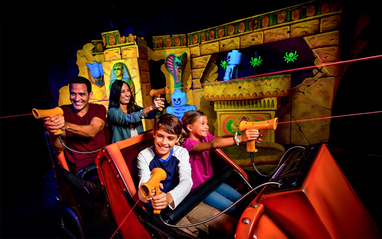 Visitors enjoying the Lost Kingdom ride at LEGOLAND Florida, aiming laser guns at targets.