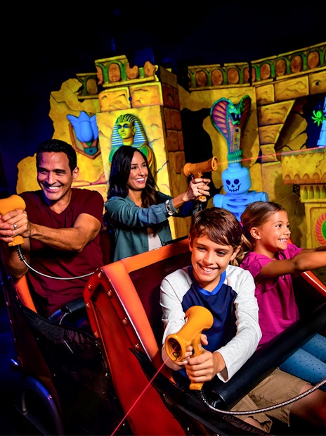 Visitors enjoying the Lost Kingdom ride at LEGOLAND Florida, aiming laser guns at targets.