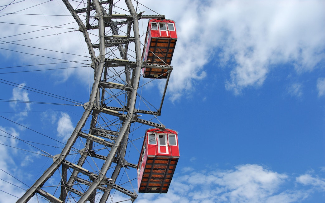 Red cabins on the Vienna Ferris Wheel against a blue sky.