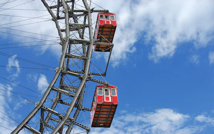 Red cabins on the Vienna Ferris Wheel against a blue sky.