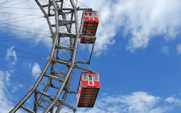 Red cabins on the Vienna Ferris Wheel against a blue sky.
