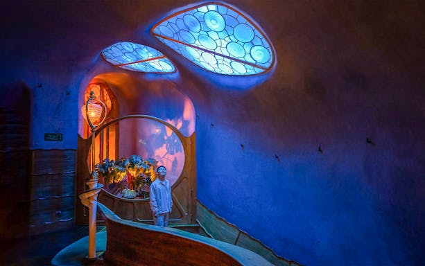 Visitor admiring the illuminated interior of Casa Batlló in Barcelona at night.