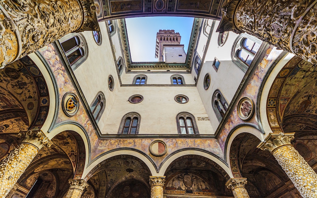 Palazzo Vecchio courtyard with ornate columns and tower view, Florence, Italy.