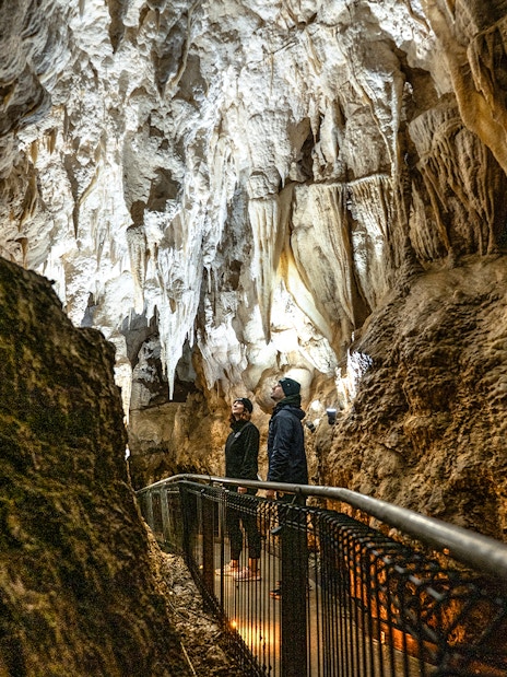Visitors exploring stalactites in Ruakuri Cave, New Zealand.