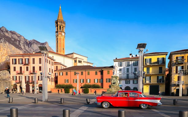Historic square in Como with colorful buildings and a classic car.
