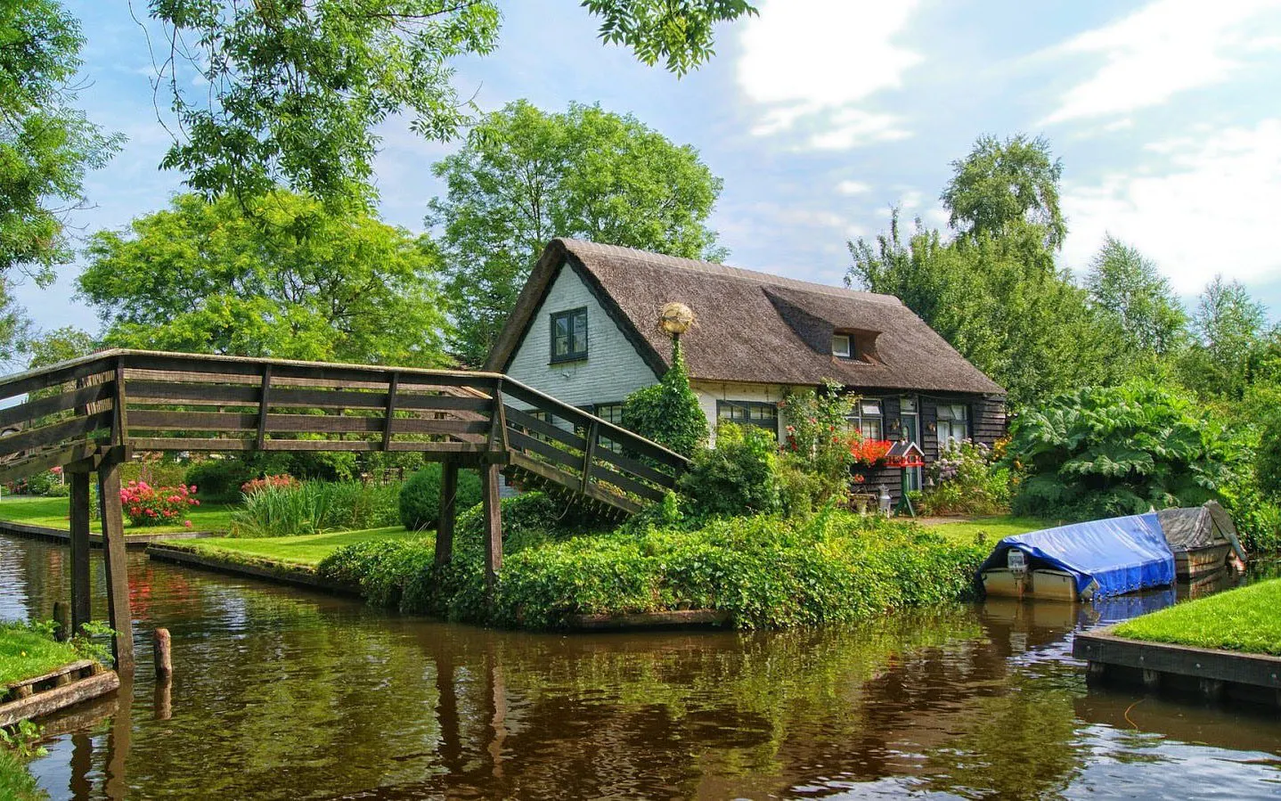 Thatched-roof house and wooden bridge over canal in Giethoorn, Netherlands.