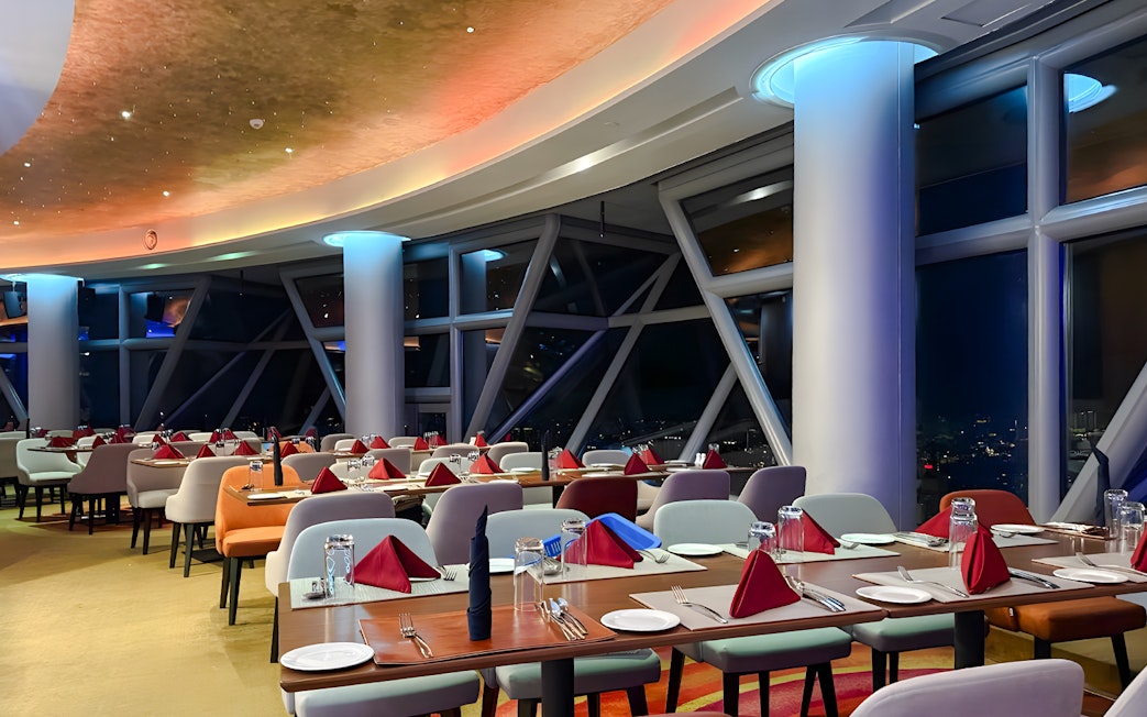 Dining area at Orbit Revolving Restaurant, KL Tower, Kuala Lumpur, with city skyline view.