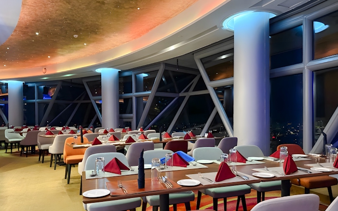 Dining area at Orbit Revolving Restaurant, KL Tower, Kuala Lumpur, with city skyline view.