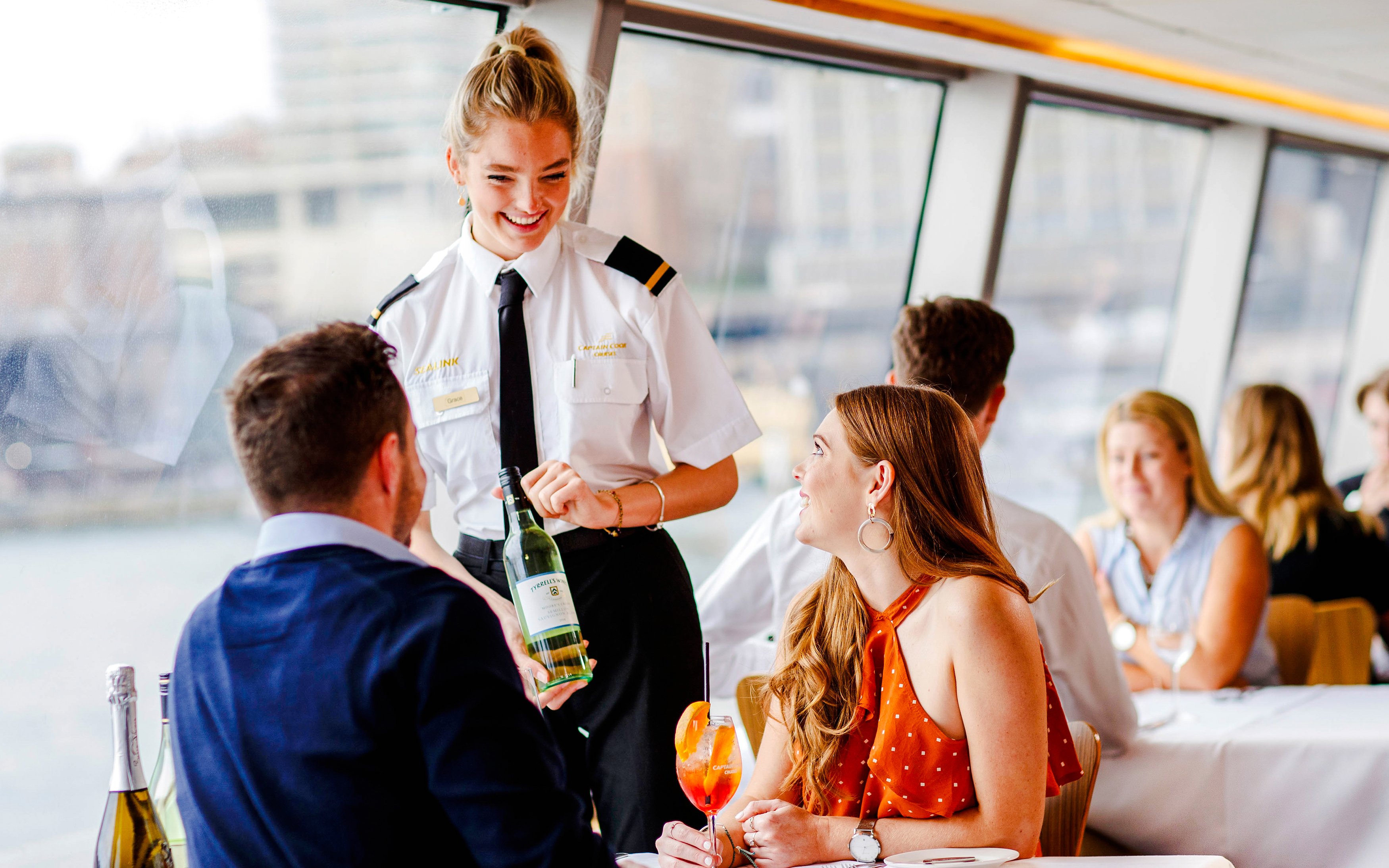 Server presenting wine to guests on a Sydney dinner cruise.