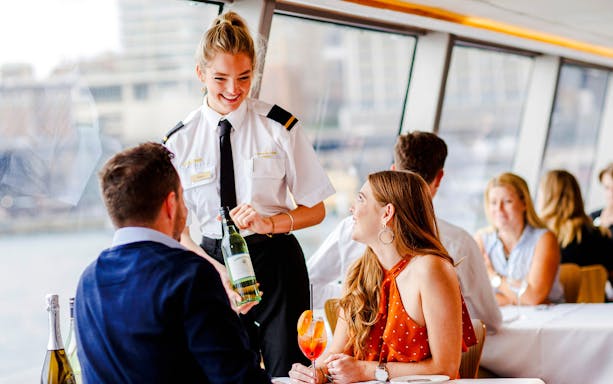 Server presenting wine to guests on a Sydney dinner cruise.