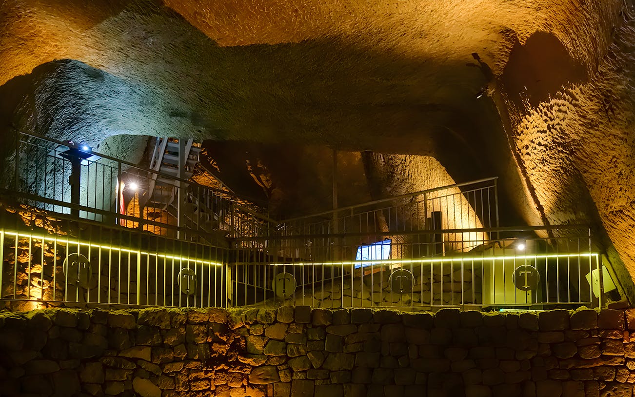 Underground chamber with stone walls and railings at LAPIS Museum, Naples.