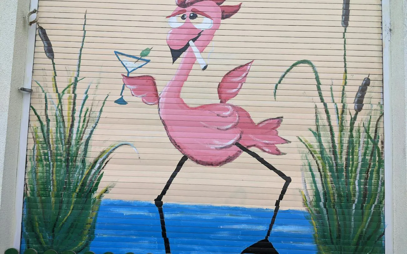 Flamingo mural with cocktail on a shutter in Bucharest, part of the Theatrical Odyssey tour.