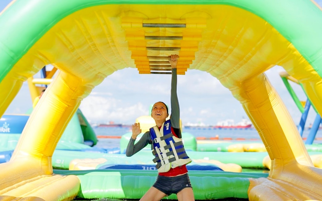 Person climbing inflatable obstacle at HydroDash Singapore water park.