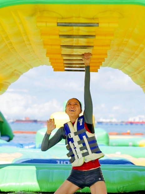 Person climbing inflatable obstacle at HydroDash Singapore water park.