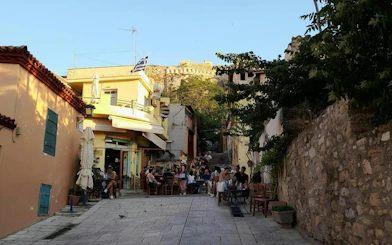Plaka street scene with outdoor café and view of Acropolis, Athens.