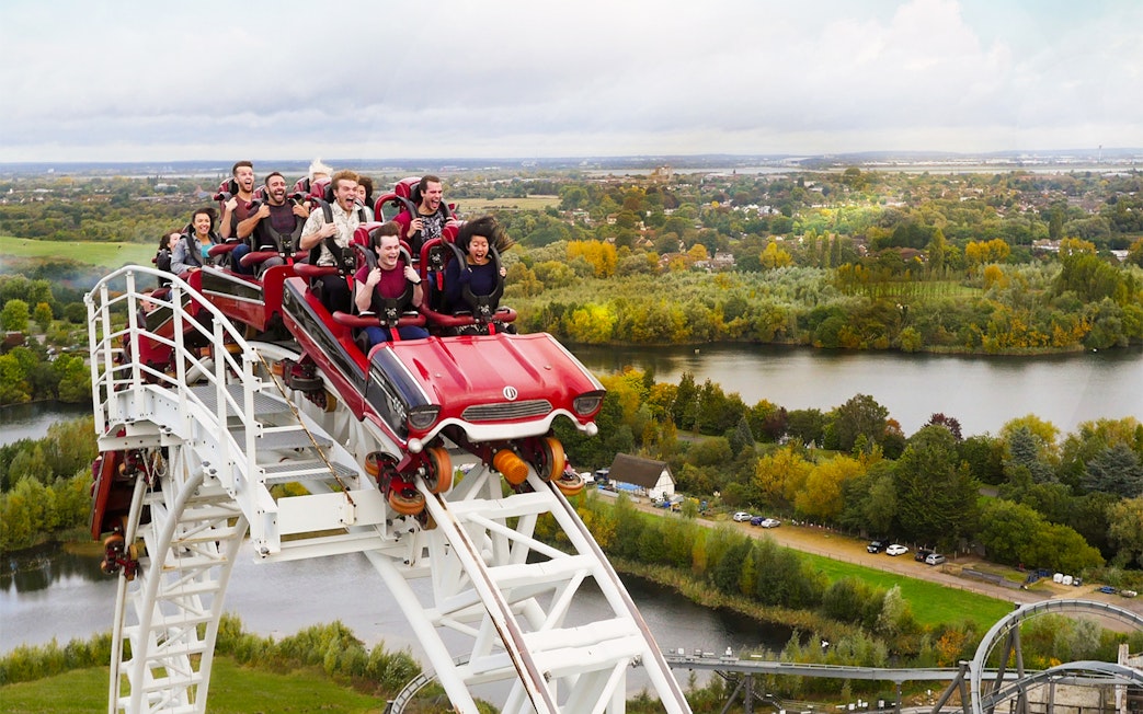 Roller coaster descending at Thorpe Park with riders enjoying the view of surrounding landscape.