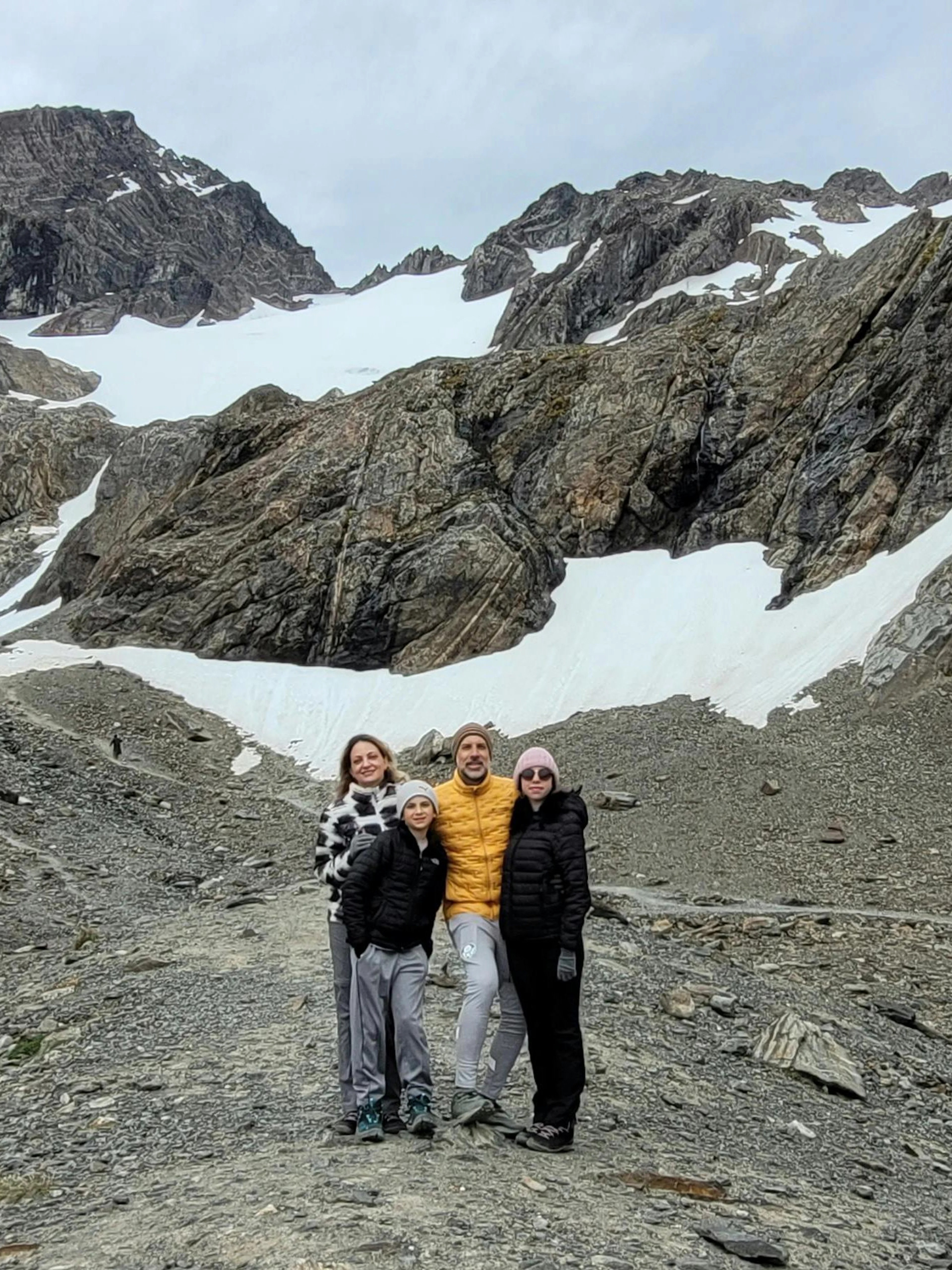 Tourists standing on Ushuaia Martial Glacier with rocky terrain and snow patches.