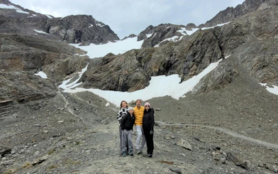 Tourists standing on Ushuaia Martial Glacier with rocky terrain and snow patches.
