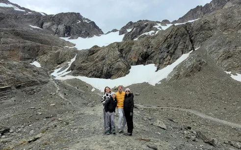 Tourists standing on Ushuaia Martial Glacier with rocky terrain and snow patches.