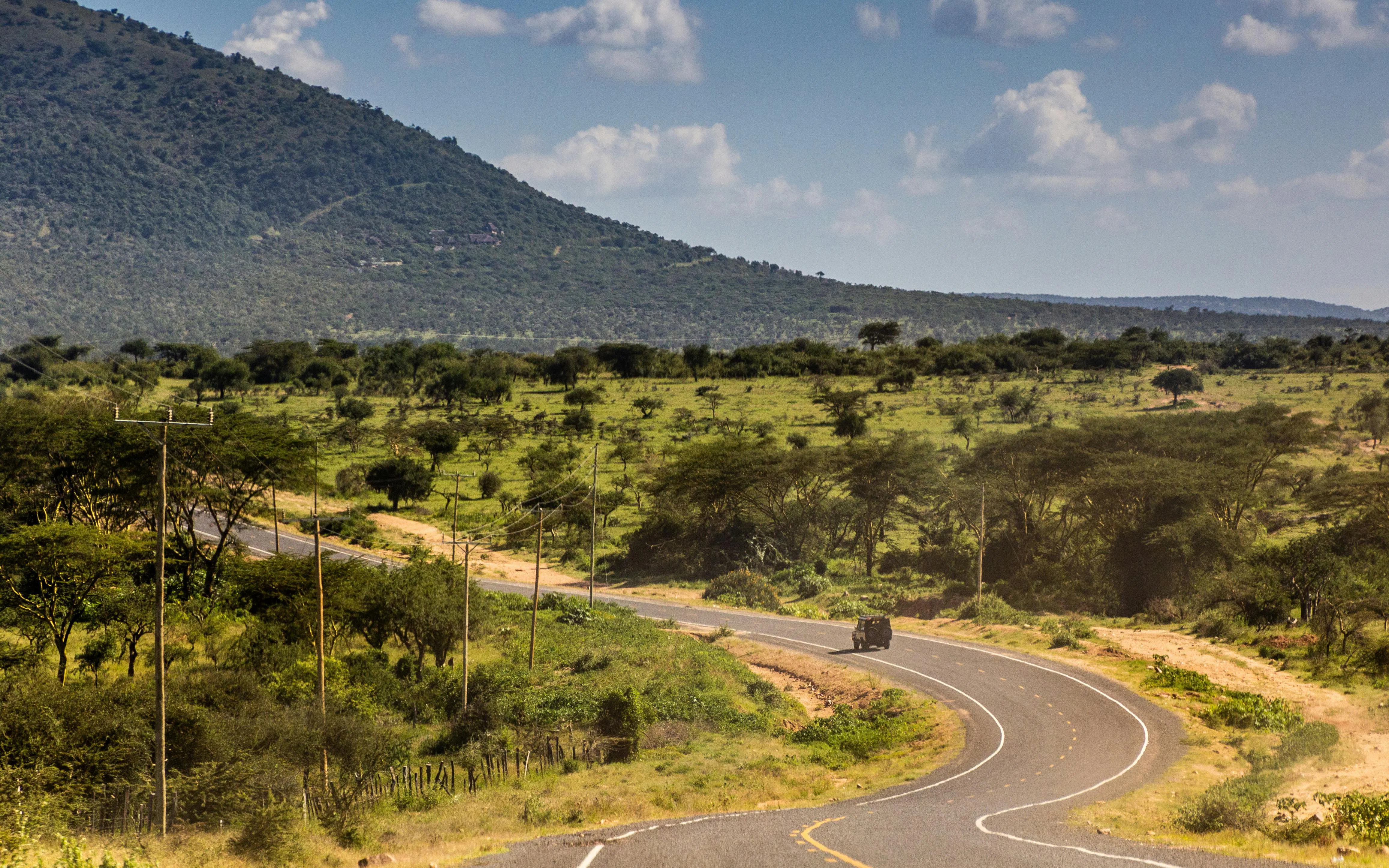 Curving road through savannah landscape between Narok and Masai Mara, Kenya.
