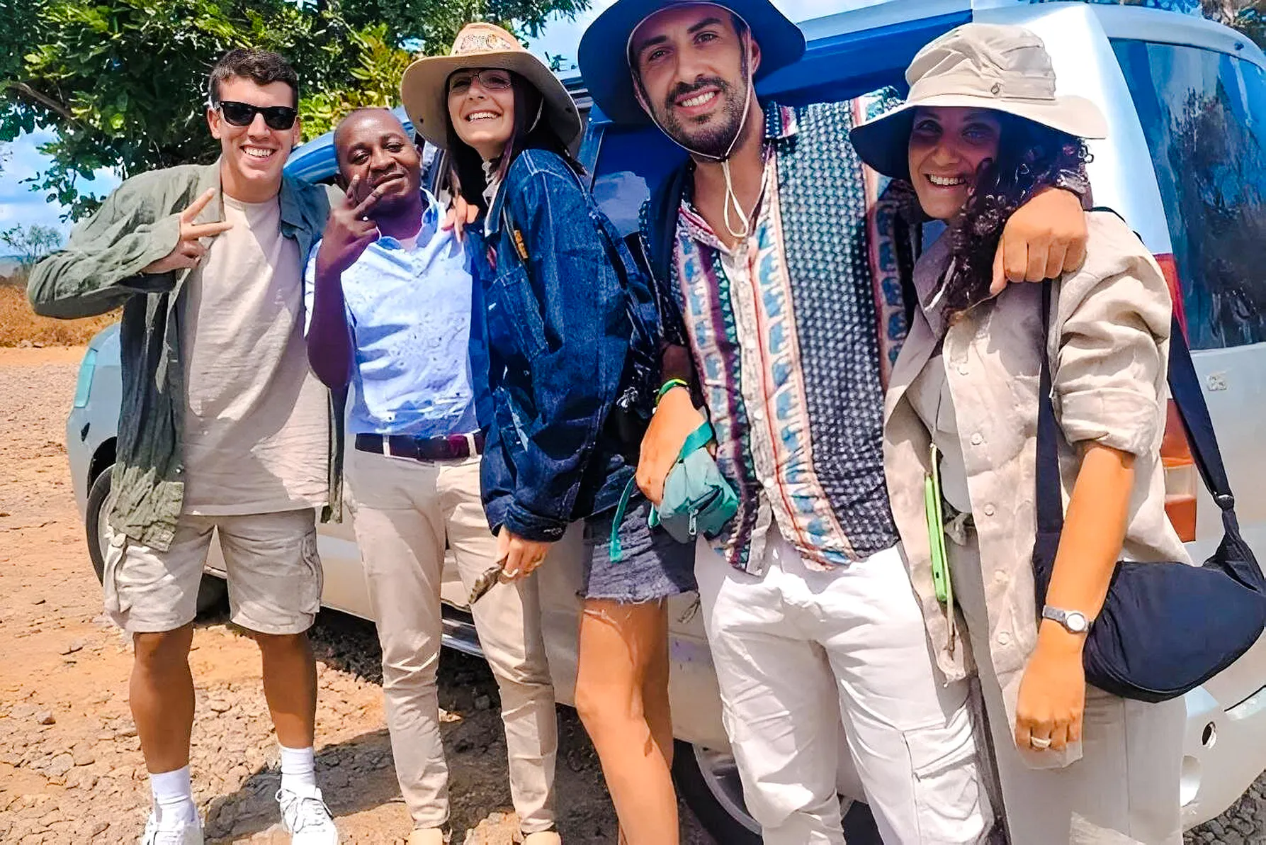 Group of tourists smiling near a safari vehicle on Mikumi Wildlife Safari from Dar es Salaam, Zanzibar.