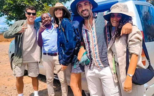 Group of tourists smiling near a safari vehicle on Mikumi Wildlife Safari from Dar es Salaam, Zanzibar.