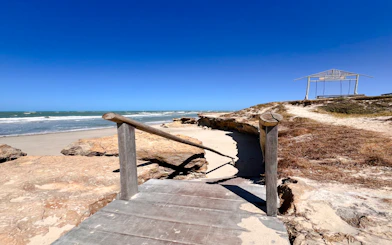 Wooden walkway leading to Pontal de Maceió beach, Fortim, with ocean view.