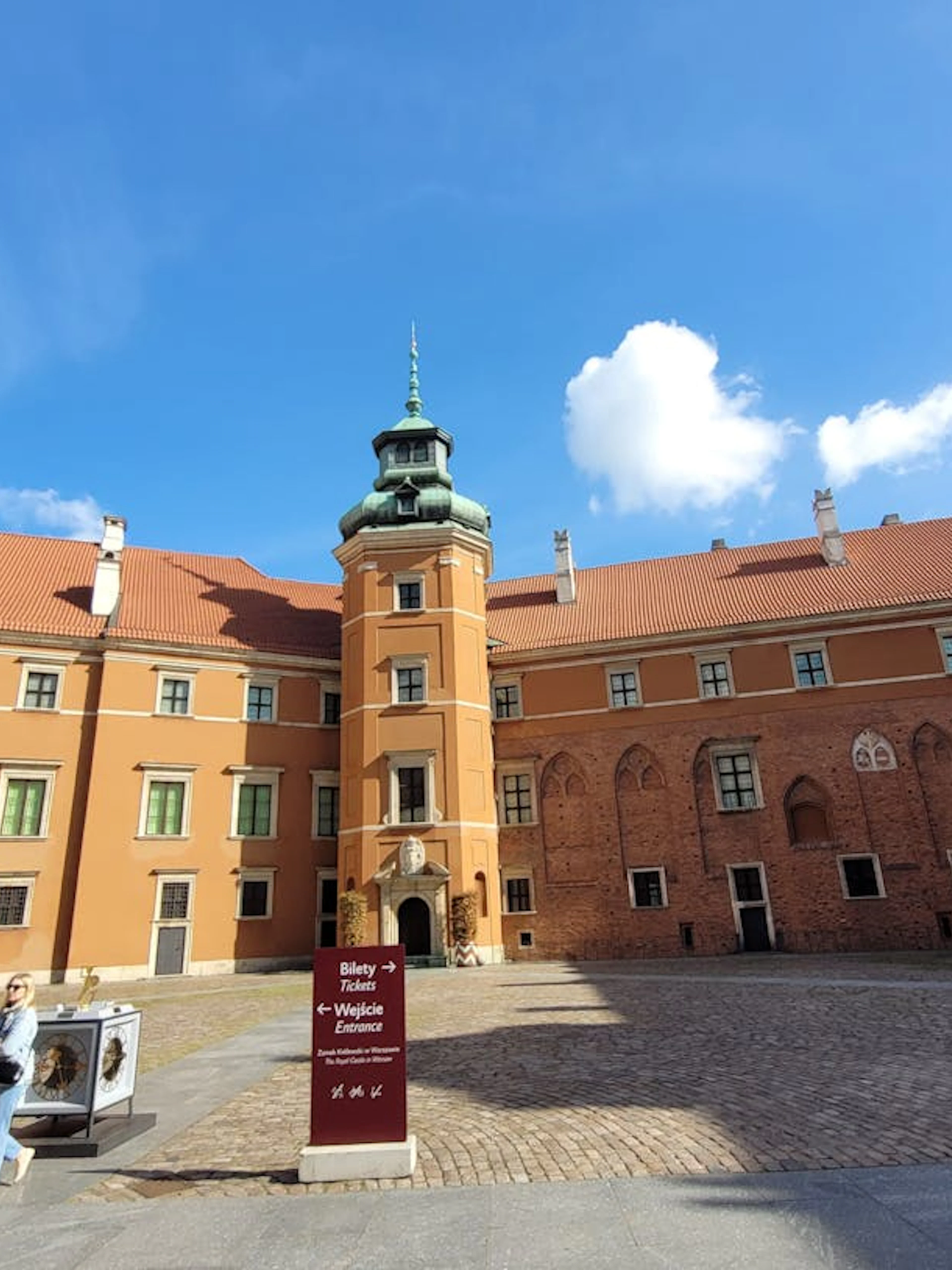 Warsaw Royal Castle courtyard with entrance sign for guided tour.