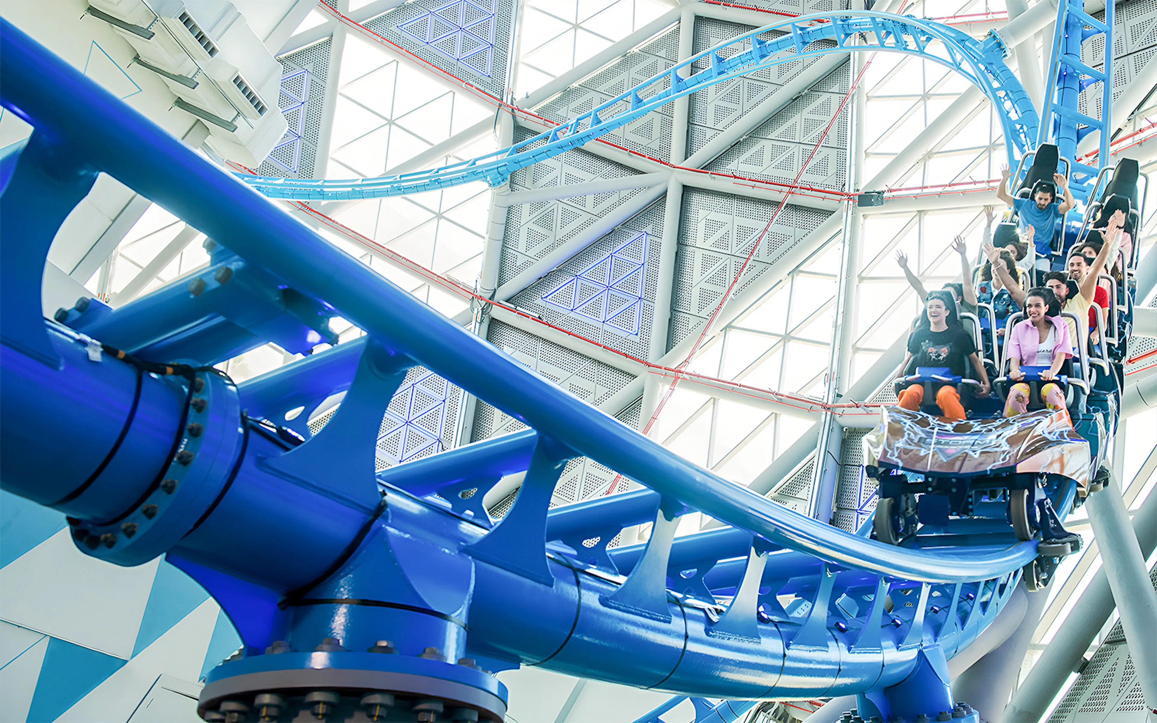 Roller coaster riders on Storm Coaster Dubai inside a modern architectural structure.