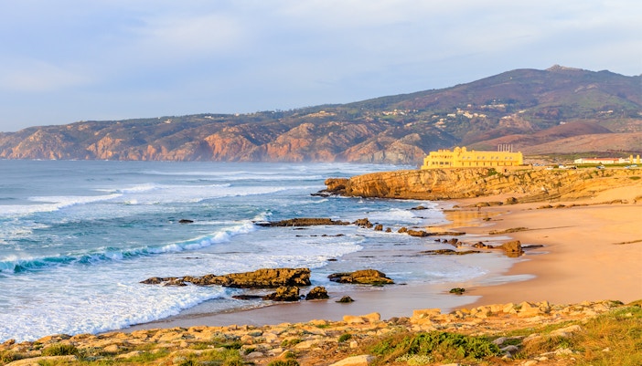 Panoramic view of Guincho Beach in Cascais with waves and rocky coastline.