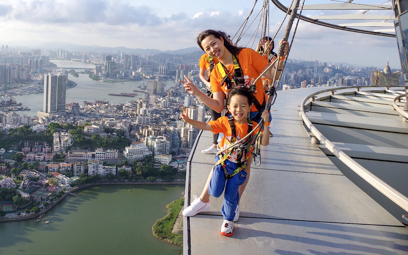 Visitors enjoying the Skywalk at Skypark Macau by AJ Hackett with cityscape view.