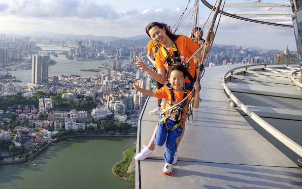 Visitors enjoying the Skywalk at Skypark Macau by AJ Hackett with cityscape view.