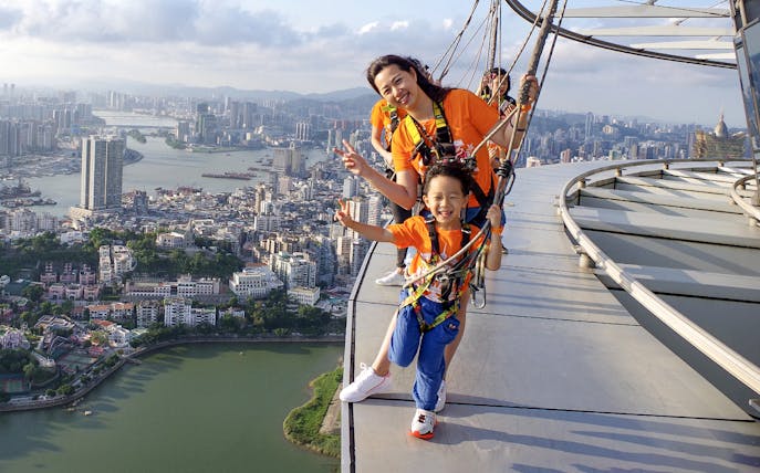Visitors enjoying the Skywalk at Skypark Macau by AJ Hackett with cityscape view.