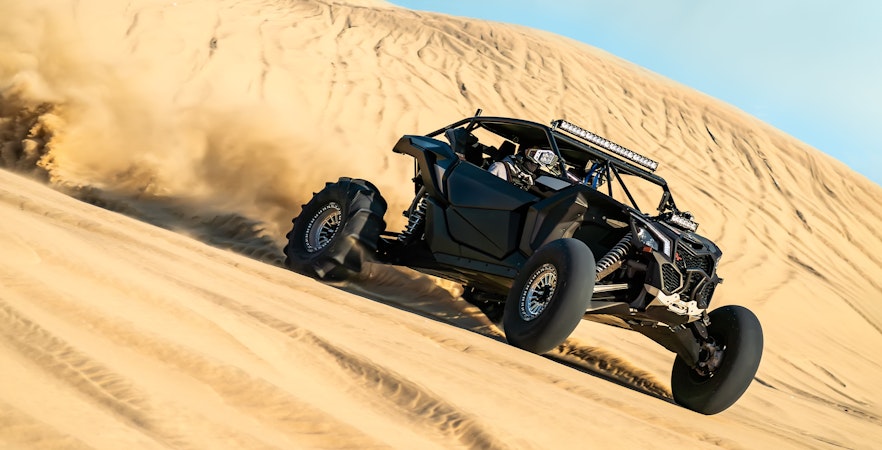 Off-road buggy driving on sand dunes in Dubai desert.