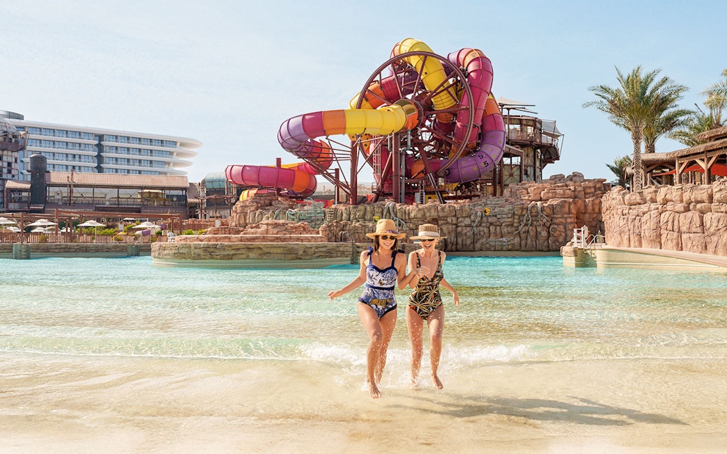 Visitors enjoying a water ride at Meryal Waterpark with colorful slides in the background.