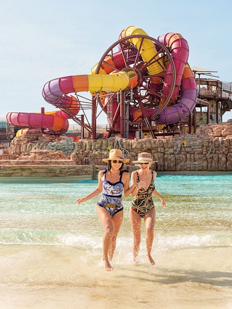 Visitors enjoying a water ride at Meryal Waterpark with colorful slides in the background.