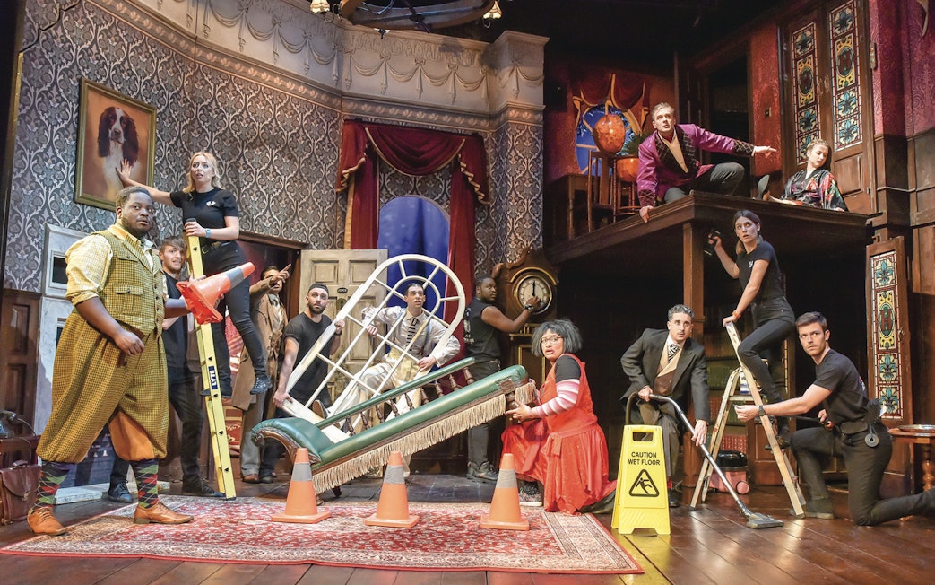 Cast performing a chaotic scene from "The Play That Goes Wrong" on stage.