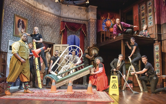 Cast performing a chaotic scene from "The Play That Goes Wrong" on stage.