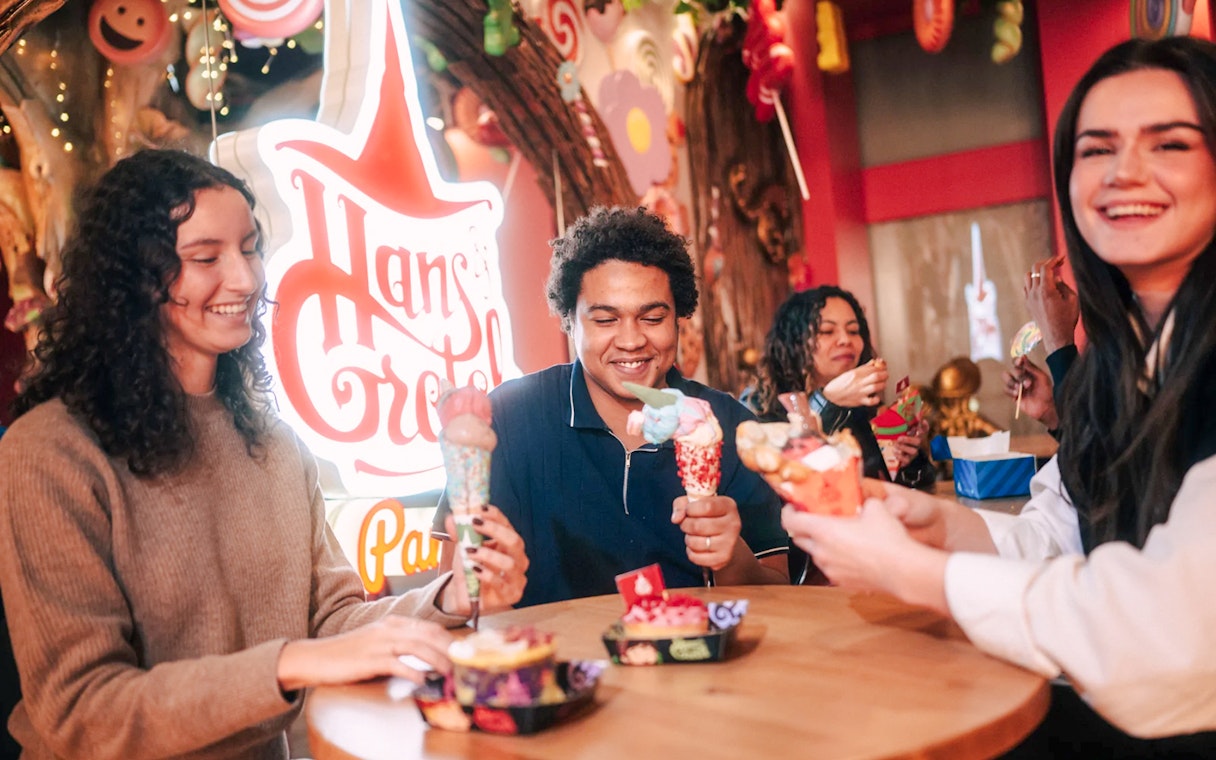 Visitors enjoying colorful desserts at Hansel and Gretel restaurant in Paradox Museum Paris.