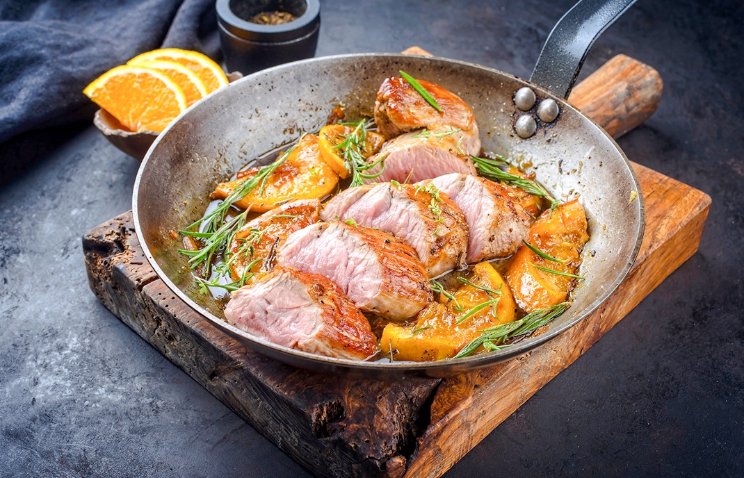 Iberian pork loin with oranges and rosemary in a pan at Montjuïc restaurant.